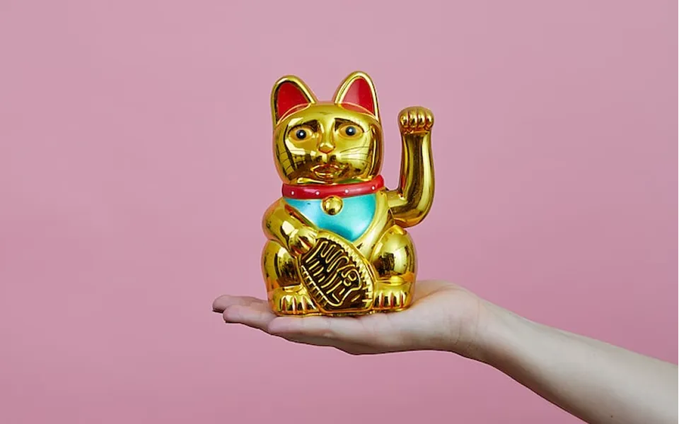 手の上に金色の招き猫が乗っています